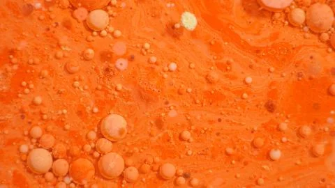 Bright colorful orange bubbles on the surface of the water. Abstract paint bu Illustrazione stock