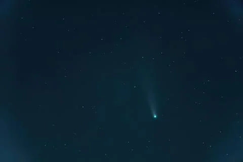 Bright comet with tail in dark night sky filled with stars Stock Photos