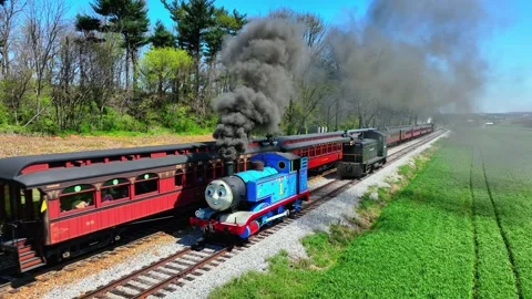 A bright day shows a Thomas the Engine moving on tracks with smoke billowing Stock Footage 336109730