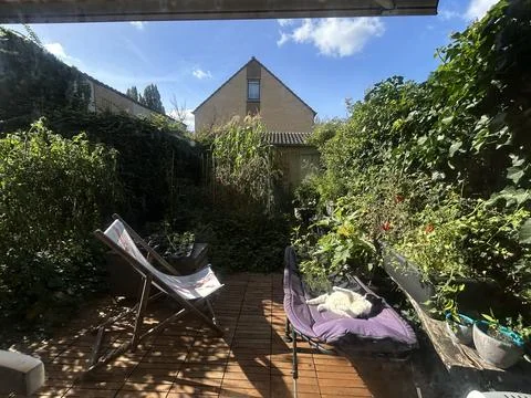 Bright daytime view of cozy backyard garden featuring wooden deck, striped Stock Photos