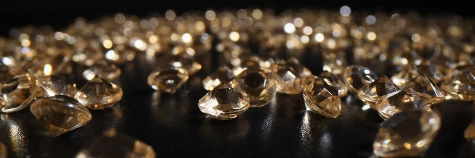 Bright diamonds scattered on dark table leaving reflection Stock Photos