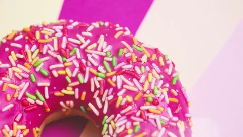 Bright donut in a pink glaze with a multi-colored sprinkle on a pink background. Stock Footage 150234932