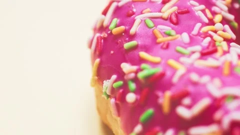 Bright donut in a pink glaze with a multi-colored rainbow sprinkle on a pink Stock Footage 150890847
