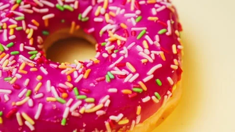 Bright donut in a pink glaze with a multi-colored rainbow sprinkle on a pink Stock Footage 151101982