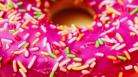 Bright donut in a pink glaze with a multi-colored rainbow sprinkle on a pink Stock Footage 151163111