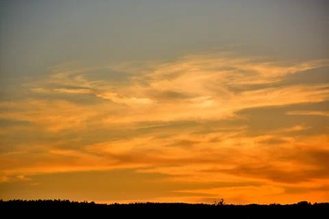 Bright dramatic clouds lit by the setting sun which descended in the evening twi Stock Photos