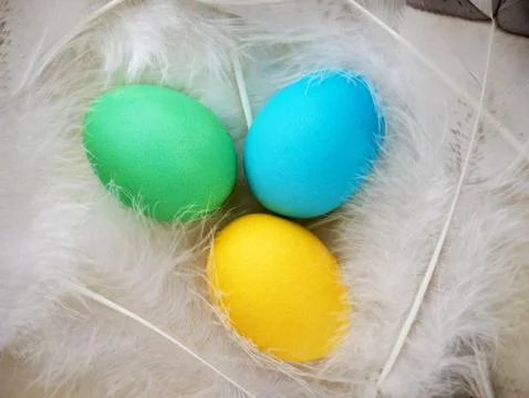 Bright Easter. Bright colorful Easter eggs on soft fluffy feathers. Close-u.. Stock Photos