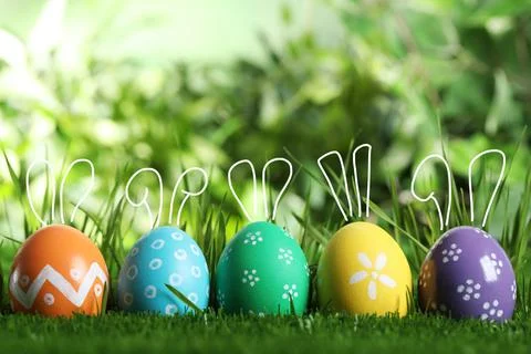 Bright Easter eggs with cute bunny ears in green grass Stock Photos