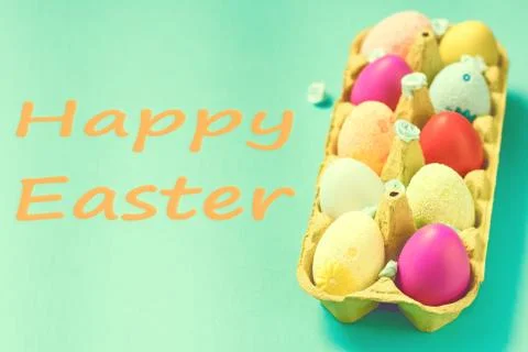 Bright Easter eggs lie in a box on a blue background Stock Photos