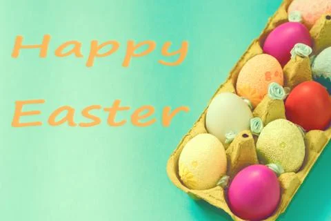 Bright Easter eggs lie in a box on a blue background Stock Photos