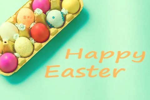 Bright Easter eggs lie in a box on a blue background Stock Photos