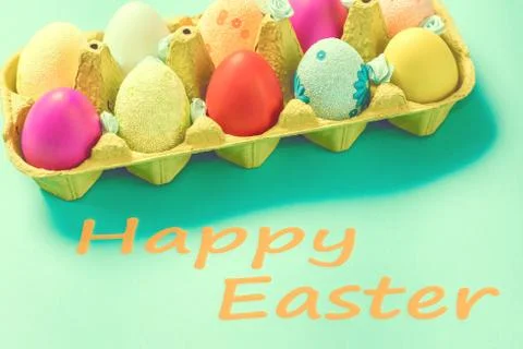 Bright Easter eggs lie in a box on a blue background Stock Photos