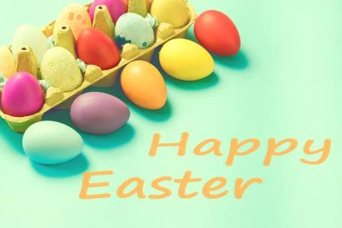 Bright Easter eggs lie in a box on a blue background Stock Photos