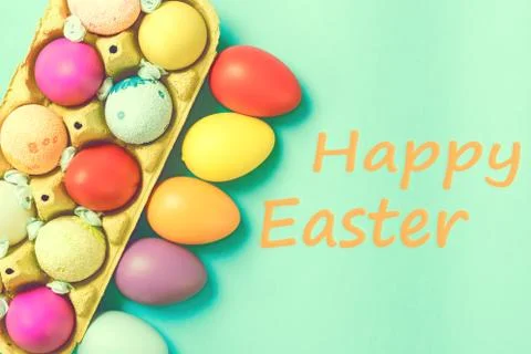 Bright Easter eggs lie in a box on a blue background Stock Photos