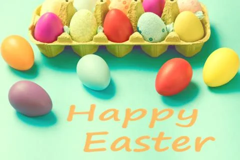 Bright Easter eggs lie in a box on a blue background Stock Photos