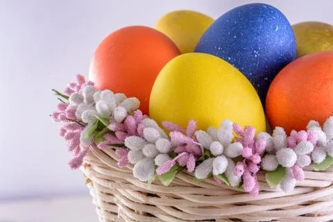 Bright easter eggs in wicker basket Stock Photos