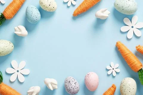 Bright Easter frame with orange carrots, white bunnies, colored eggs and flow Stock Photos
