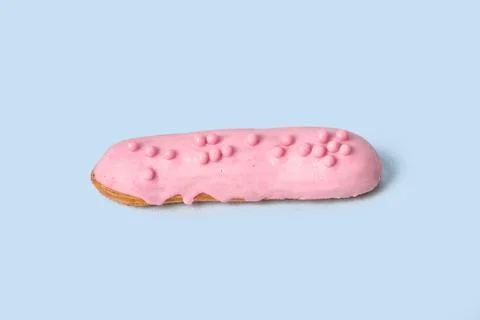 Bright Eclair in pink glaze sprinkled with colorful pink jelly beans, balls. Stock Photos