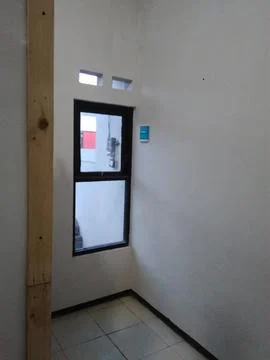 A bright, empty room corner with plain white walls, a black-framed window, an Stock Photos
