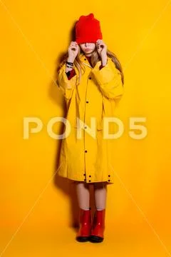 A bright fashionable girl in a raincoat and a hat. Autumn fashion for kids. Stock Photos