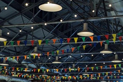 Bright festive flags and glowing string lights hang across modern industrial Stock-Fotos