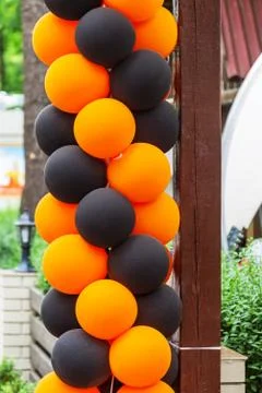 Bright festive multi-colored inflatable balls, black and orange, are woven in Foto stock