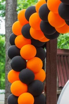 Bright festive multi-colored inflatable balls, black and orange, are woven in Stock Photos