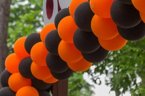 Bright festive multi-colored inflatable balls, black and orange, are woven in Stock Photos