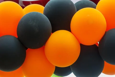Bright festive multi-colored inflatable balls, black and orange, are woven in Stock Photos