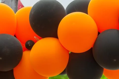 Bright festive multi-colored inflatable balls, black and orange, are woven in Stock Photos