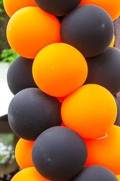 Bright festive multi-colored inflatable balls, black and orange, are woven in Stock Photos
