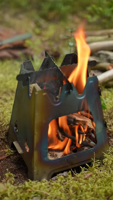 Bright fire burning inside a portable folding wood stove Stock Footage 340653494