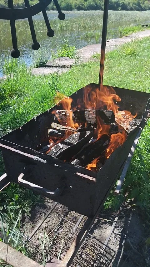 Bright fire burning in a metal grill on a riverbank Stock-Footage 342519443