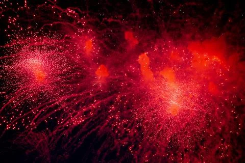A bright firework with a red glowing center with red sparks and smoke flying Stock Photos