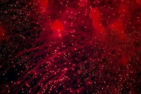 A bright firework with a red glowing center with red sparks and smoke flying Stock Photos