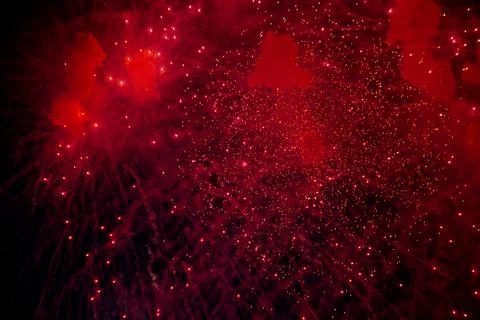 A bright firework with a red glowing center with red sparks and smoke flying Foto stock