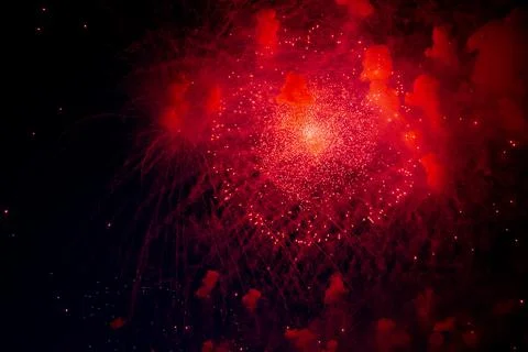 A bright firework with a red glowing center with red sparks and smoke flying Stock Photos