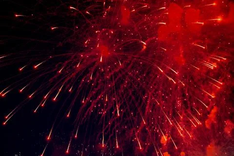 A bright firework with a red glowing center with red sparks and smoke flying Stock Photos
