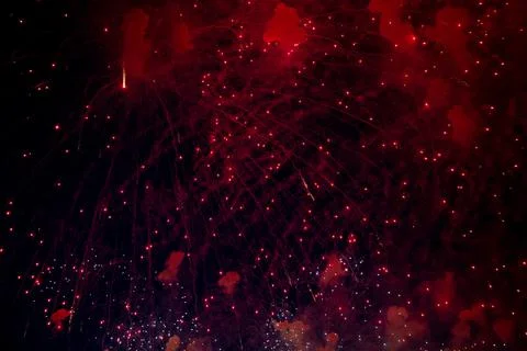 A bright firework with a red glowing center with red sparks and smoke flying Stock Photos