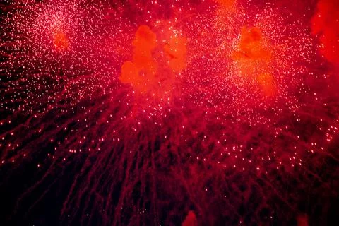 A bright firework with a red glowing center with red sparks and smoke flying Stock Photos