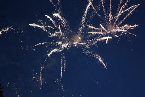 Bright fireworks explosion scattering white sparks in the dark sky Stock Photos