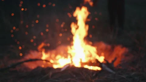 A bright flame of a bonfire in a pit on a field and sparks in the air from Stock Footage 164855434