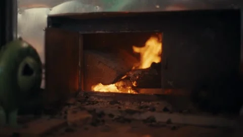 Bright flames dance inside a metal stove, consuming firewood and filling Stock Footage 330254698