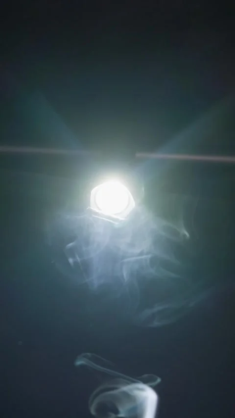 Bright Flashlight Beam Piercing Swirling Smoke in Dark Studio Close-Up Vidéo 345169733