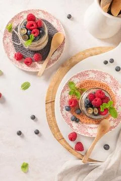 A bright flat lay features two glass jars of chia seed pudding garnished wi.. Stock Photos