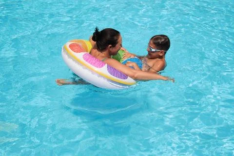 Bright float and brighter smiles; a mother-son pool day. Highlights the value of Stock Photos