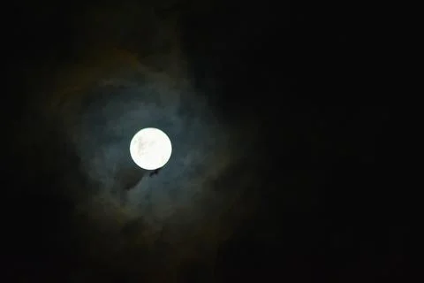 Bright full moon with halo in dramatic night clouds Stock Photos