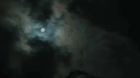 A bright full moon illuminates dramatic, dark clouds in a mysterious night sky Stock Footage 346471342