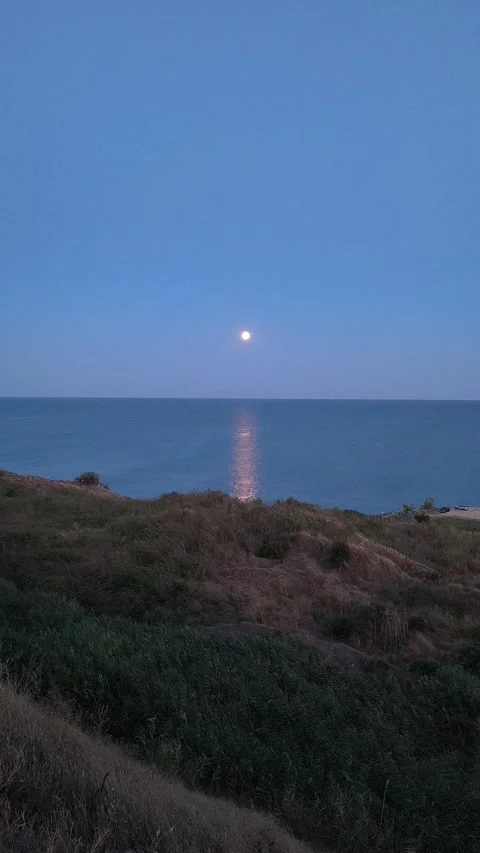 Bright full moon rising over the calm sea with a glowing light reflection on  Stock Footage 341475103