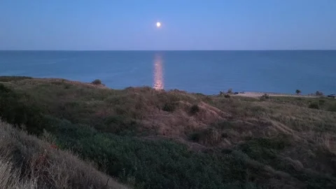 Bright full moon rising over the calm sea with a glowing light reflection on  Stock Footage 341475174